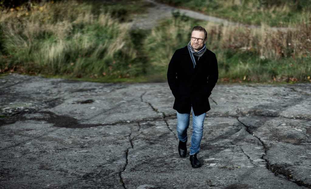 Mikko Niemelä kävelee kalliolla syksyiusessä maiisemassa.