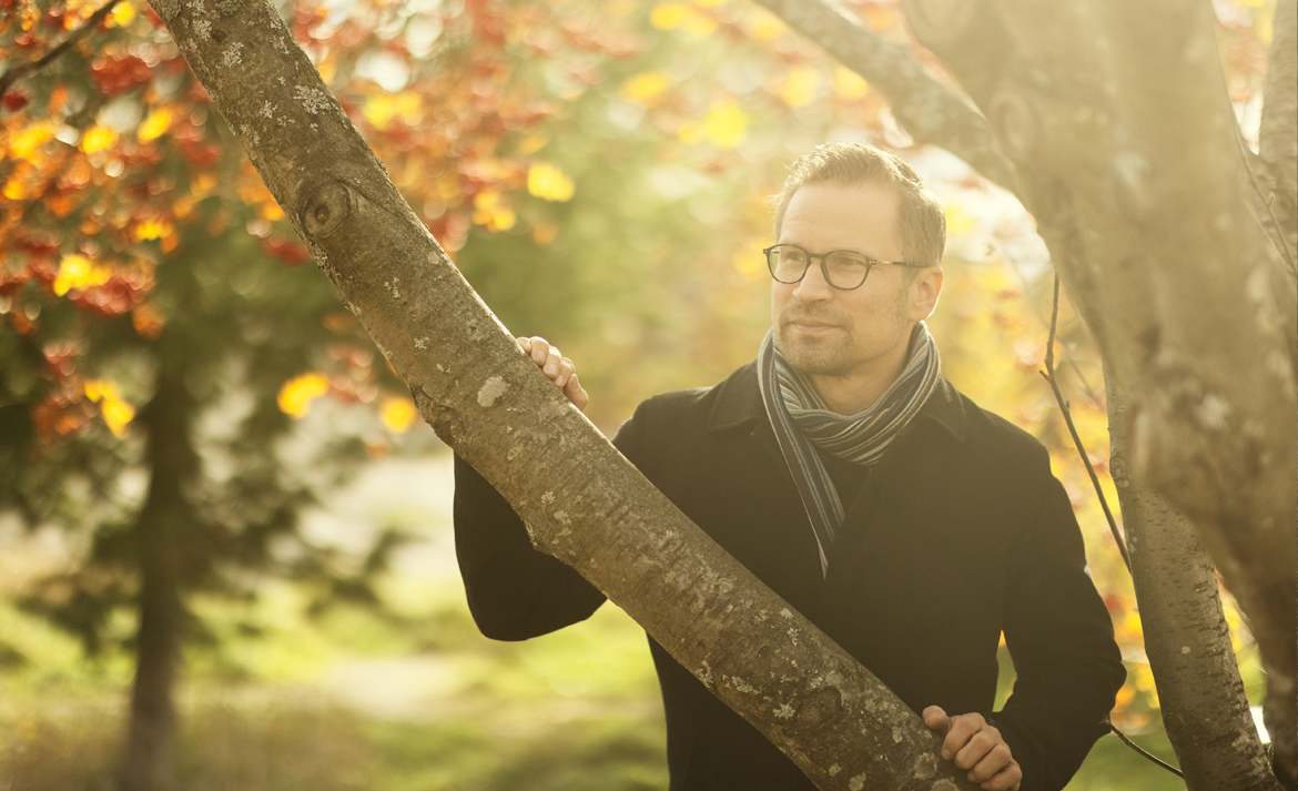 Mikko Niemelä seisoo syksyisessä maisemassa keltalehtisen puun alla.